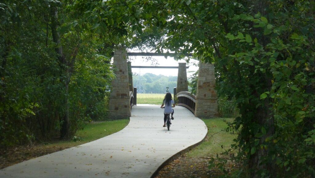 Person riding a bike down a path over a bridge