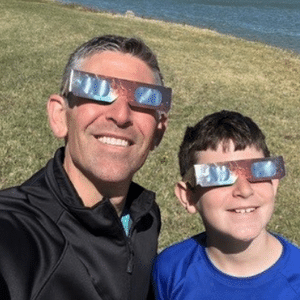 Father and son outside wearing total eclipse glasses