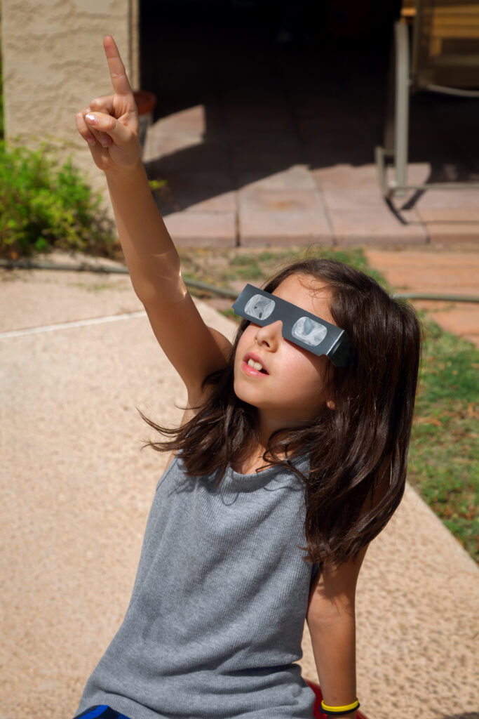 Young Girl Pointing To the Sky While Wearing Eclipse Glasses On