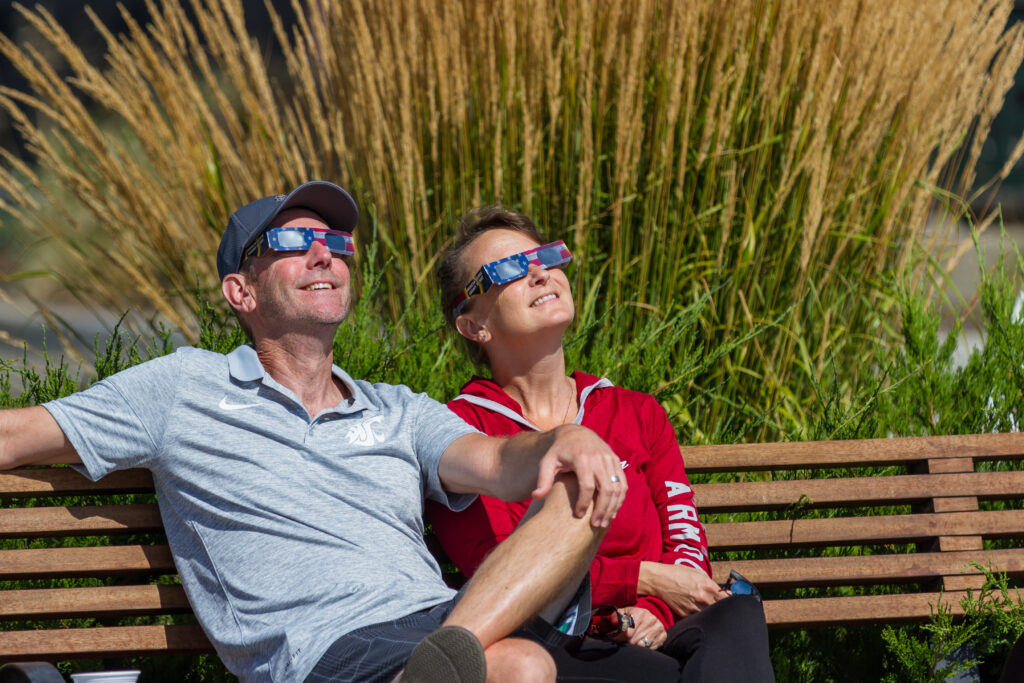 people on a bench looking at a solar eclipse