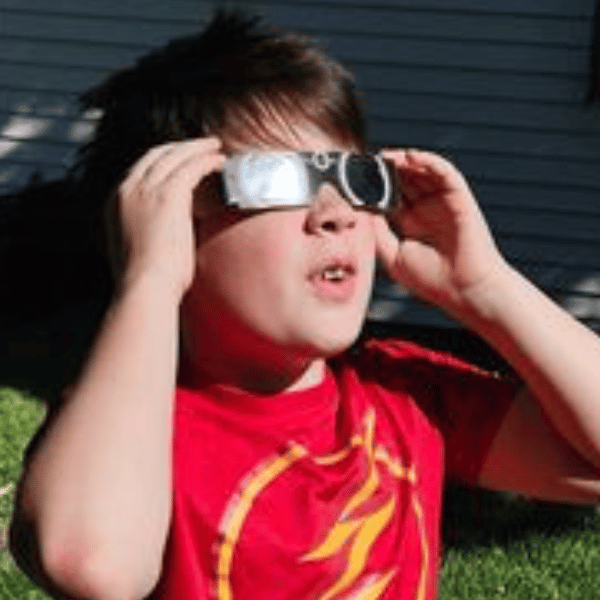 Young boy outside wearing total eclipse glasses