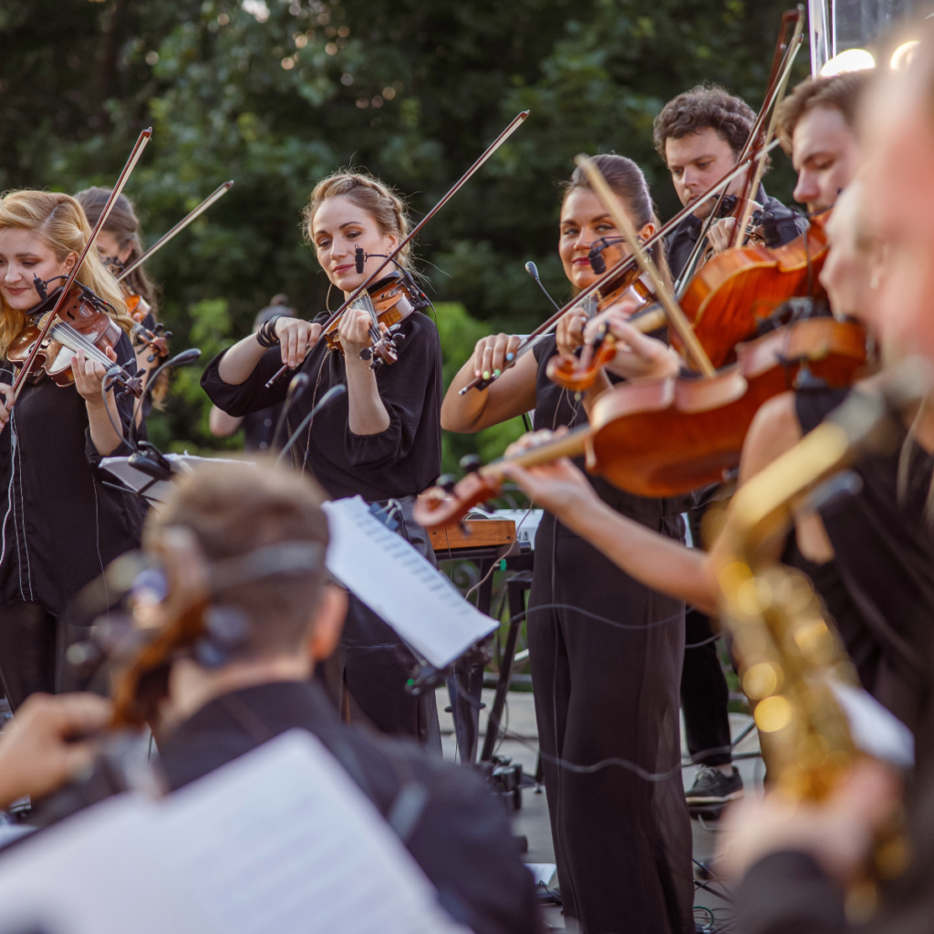 A group of musicians playing the violin outdoors