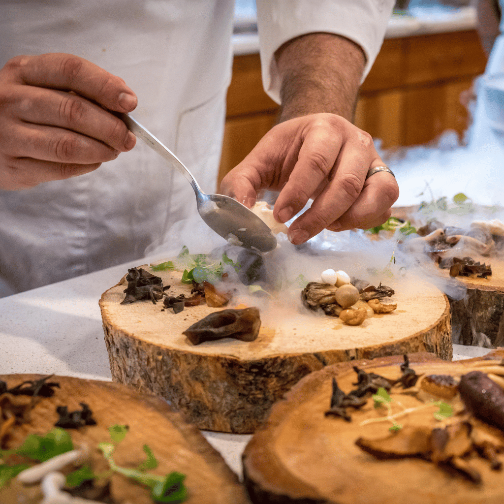 A person arranging food on a wooden stump platter.
