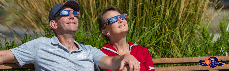 two people watching a solar eclipse with solar eclipse glasses
