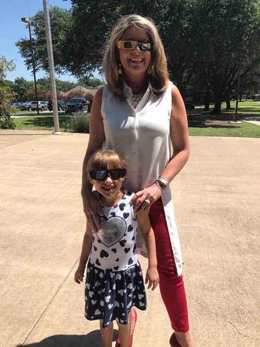 Mother and daughter outside wearing solar eclipse glasses