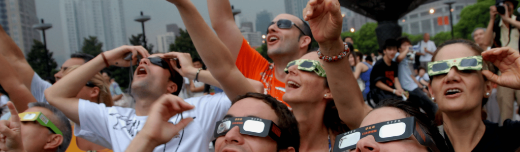 people wearing eclipse glasses and watching a solar eclipse